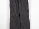un pantalon noir suspendu à un cintre devant un mur blanc