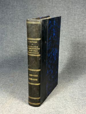 an old book with a black cover sitting on top of a table