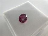a close up of a pink sapphire stone on a white surface