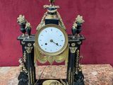 une horloge noire et dorée posée sur une table en marbre