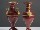 une paire de vases rouges et dorés posés sur une table blanche