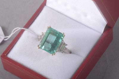 a ring in a red box with a green stone in it