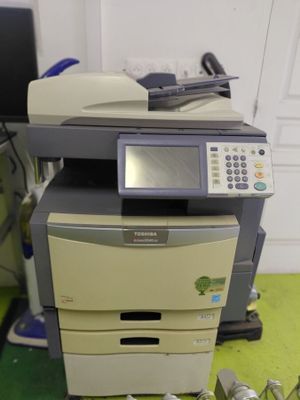 une imprimante posée sur un bureau, à côté d'une pile de papiers