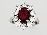 a close up of a ring with a red stone surrounded by white diamonds