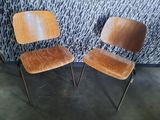 two wooden chairs sitting next to each other in front of a wall
