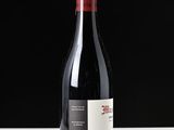 a bottle of red wine sitting on a white table