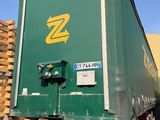 un gros camion vert garé à côté d'un tas de bois