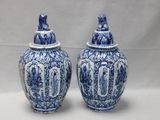 Deux vases bleus et blancs munis d'un couvercle sont posés sur une table.