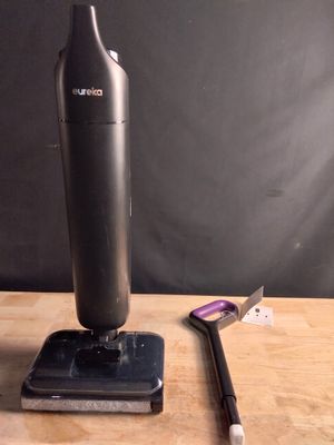 un aspirateur noir et argent posé sur une table à côté d'une brosse à dents