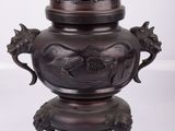 une image représentant un vase en bronze posé sur une surface blanche