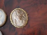 three antique cameos of women on a table next to a feather