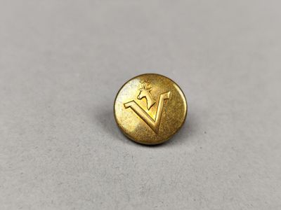 un petit bouton en laiton sur lequel figure la lettre « v »