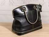 black leather handbag on a wooden table with a white wall in the background