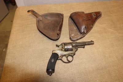 deux vieux pistolets et un étui en cuir posés sur une table