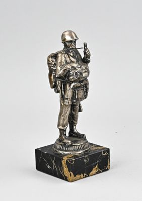 silver figurine of a soldier with a gun on a marble base