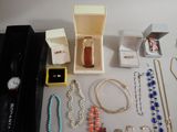 a lot of jewelry sitting on a table with a watch