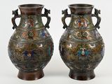 une paire de vases anciens posés sur une surface blanche