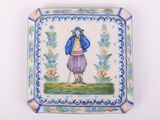 une petite assiette sur laquelle est représenté un homme portant une veste bleue et un chapeau