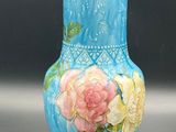 a blue vase with pink and yellow flowers painted on it