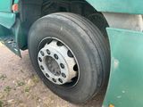 a green truck with a flat tire parked on the side of the road