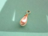 une petite perle rose suspendue à un pendentif plaqué or