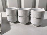 four white cups sitting on top of a table next to each other