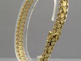 un gros plan d'un bracelet plaqué or posé sur un socle transparent