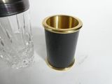 a black and gold cup next to a glass on a table