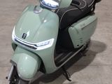 un scooter vert clair garé sur un parking