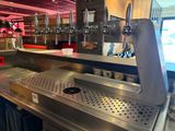 a metal counter with a bunch of beer taps on it