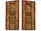 two gold and red military badges with a crown on each of them