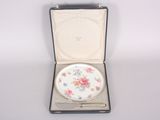 a small white plate in a case with flowers on it