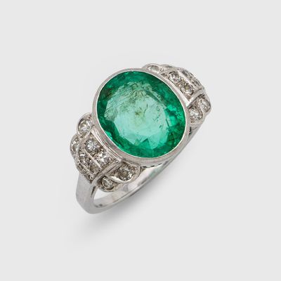 gros plan d'une bague avec une pierre verte entourée de diamants