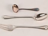 three spoons and a fork on a white table