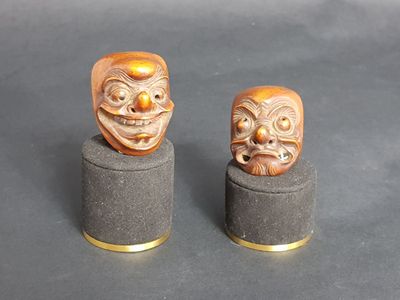 two wooden masks sitting on top of each other