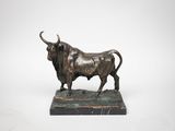 une image représentant une statue de taureau en bronze posée sur un socle en marbre