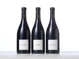 three bottles of red wine are lined up on a table