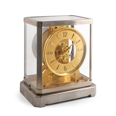 une horloge dorée placée dans une vitrine, posée sur une surface blanche