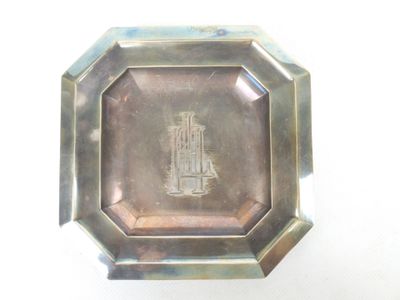 une assiette en argent sur laquelle est représenté un phare