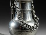 un vase en argent entouré d'une chaîne, posé sur une table