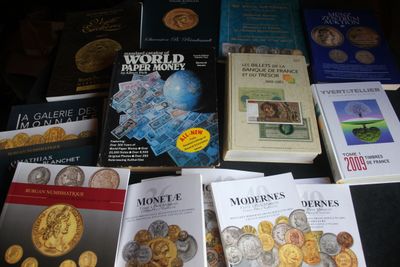 Plusieurs livres sont posés sur une table, à côté d'une pile de pièces de monnaie