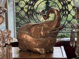une statue d'éléphant posée sur une table, à côté d'une lampe