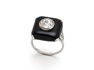 un gros plan d'une bague posée sur une surface blanche, sertie d'un diamant