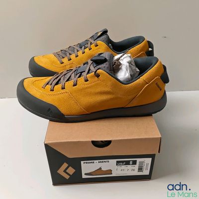 Des baskets jaunes et noires sont posées sur une boîte en carton