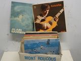 une boîte remplie de disques posée sur une table, avec une guitare à côté