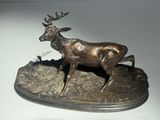 sculpture en bronze représentant un cerf aux bois imposants dans un champ