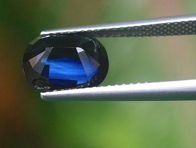 un gros plan d'un diamant bleu tenu par une pince