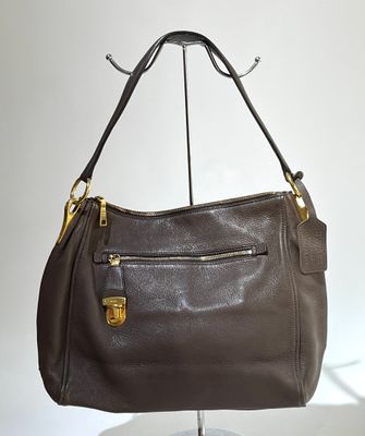 PRADA. Sac besace porté épaule en cuir couleur taupe, accast…