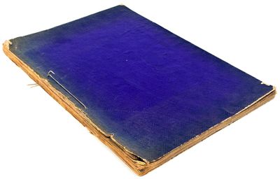 an old book with a blue cover sitting on top of a white surface