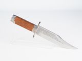 un couteau avec un manche en bois sur une surface blanche